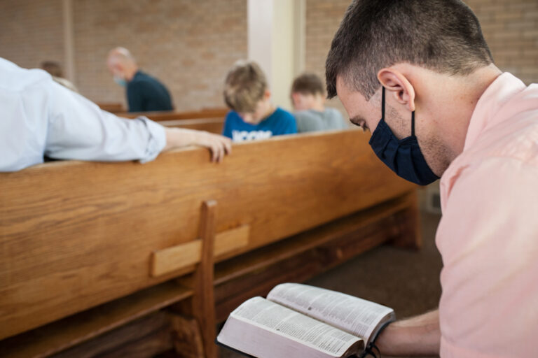 Person wearing a mask sitting in a pew during a worship service