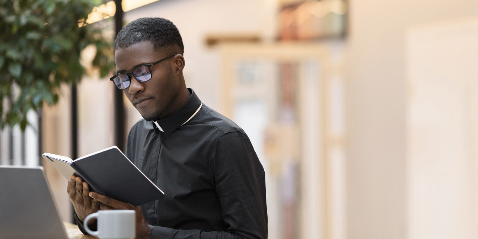 young-male-priest-reading-book-cafe-72dpi Young priest studying