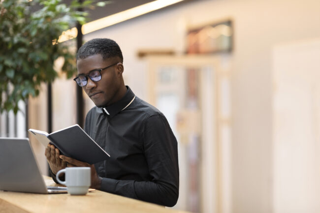 young-male-priest-reading-book-cafe-72dpi Young priest studying